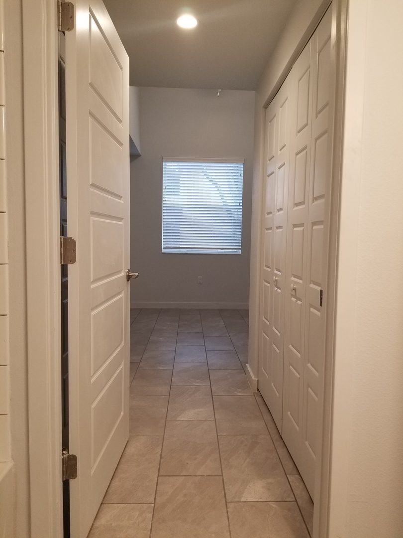Hallway with open doors and window blinds.